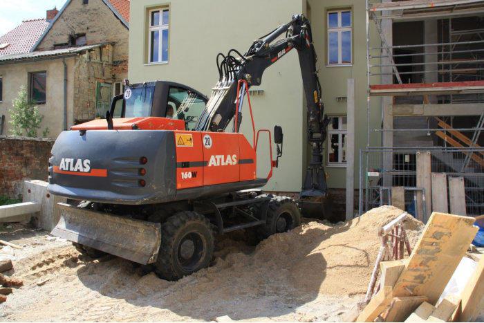 Bagger transportiert Aushub und verdichtet ihn